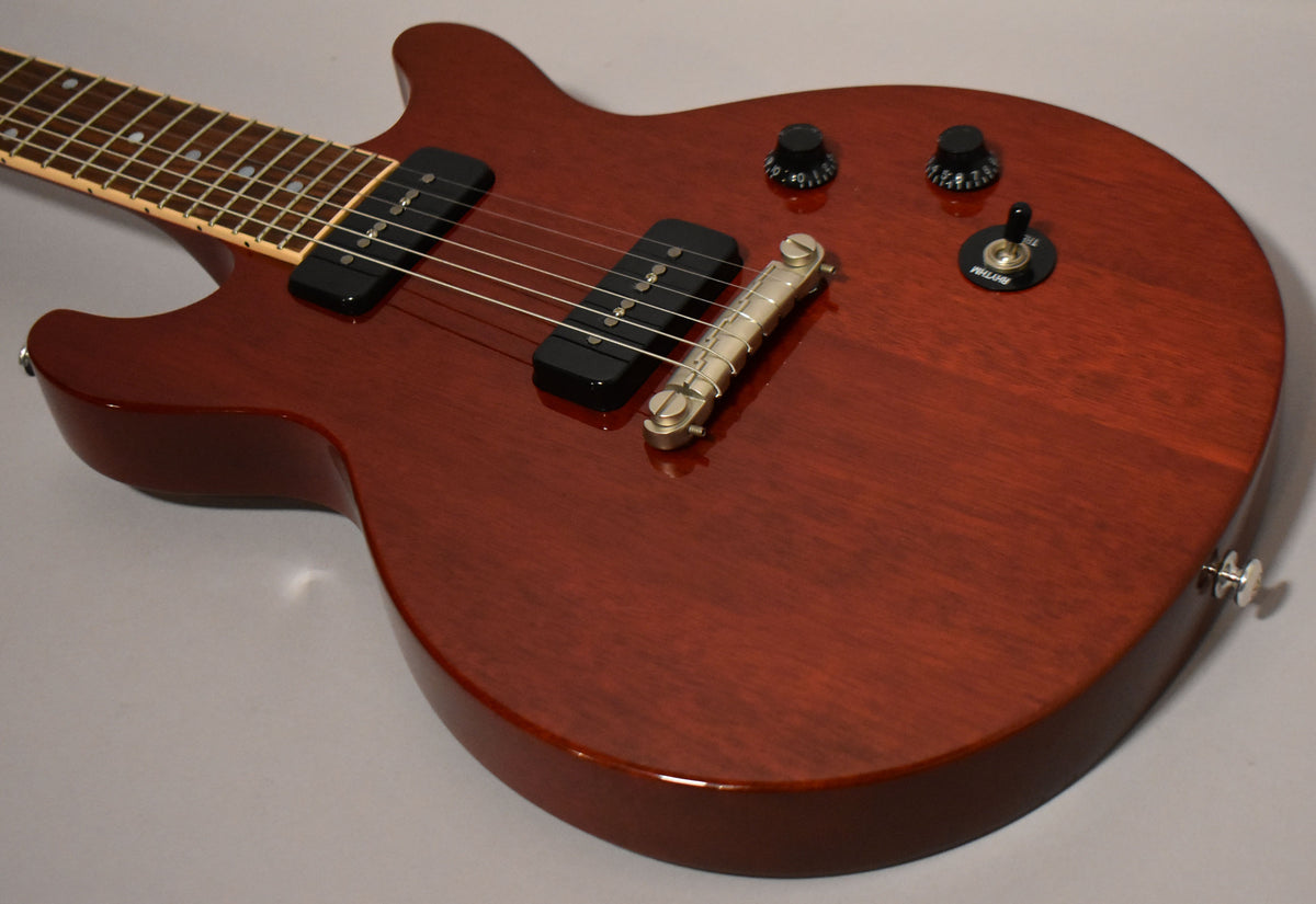 Cherry red guitar body with two black P90 pickups, a wraparound bridge, two black control knobs, and a black toggle switch.