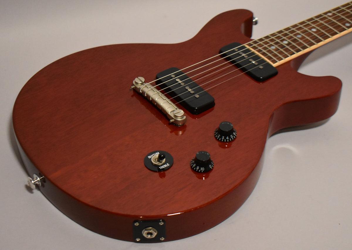 Cherry red electric guitar body, angled from the lower bout, showing two P90 pickups, a wraparound bridge, and four black control knobs.