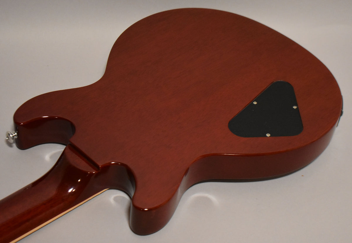 The guitar's cherry red back, with a satin finish, shows a black triangular control cavity cover and a chrome strap button.