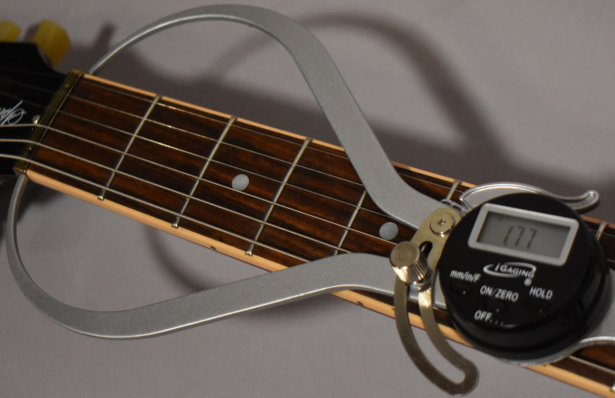 Close-up of the guitar's dark rosewood fretboard with dot inlays, showing a digital fret height gauge reading "1.77".