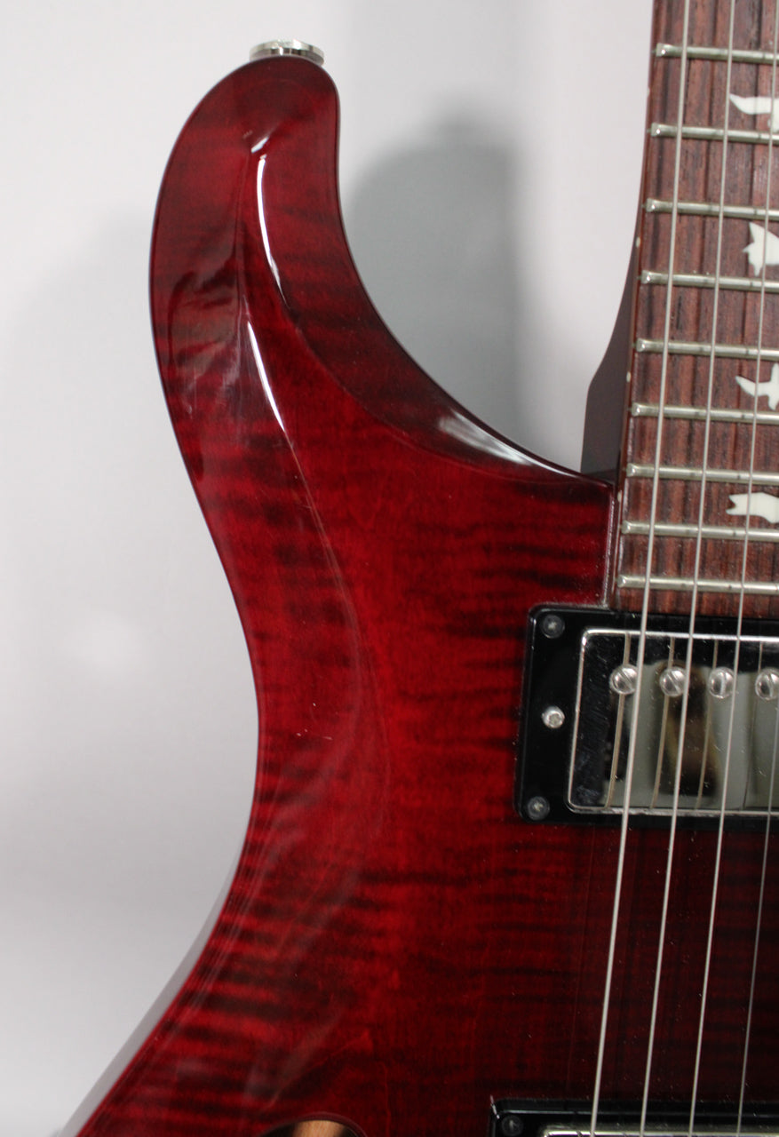Upper bout of a trans red flamed maple guitar, showing the neck joint, rosewood fretboard with bird inlays, and neck pickup.