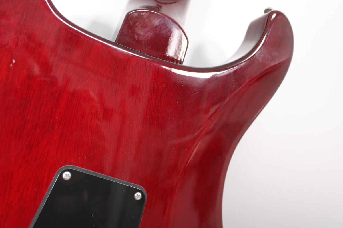 Close-up of the guitar's trans red back, showing the neck joint and a black control cavity cover, with light surface scratches visible.