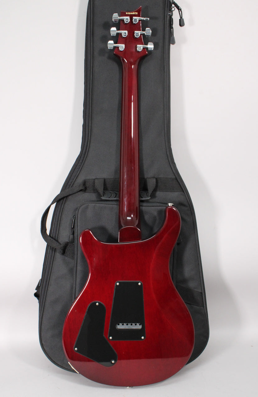 Trans red guitar, seen from the back, with a glossy finish, black control plates, and six chrome tuners on the headstock.