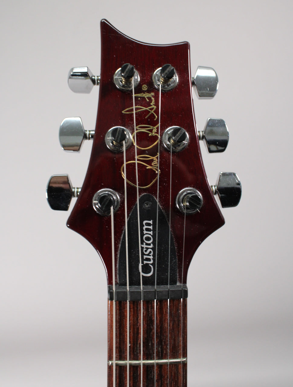 Close-up of the guitar's dark red headstock with six chrome tuners, showing the top of the fretboard and nut.
