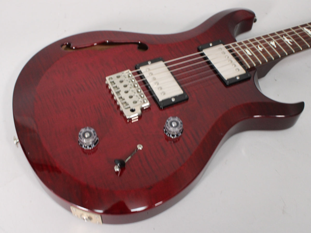 Trans red semi-hollow guitar, angled from above, showing the f-hole, two humbuckers, chrome bridge, and two clear control knobs.