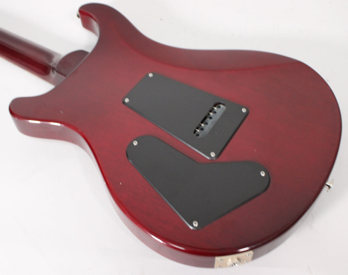 The back of a trans red guitar body, showing two black control cavity covers and a string-through-body bridge.