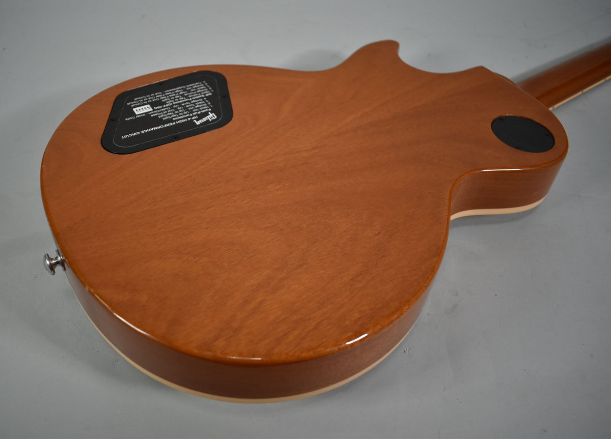 The guitar's back, a glossy brown, shows a black control cavity cover and a black circular access plate near the neck heel.