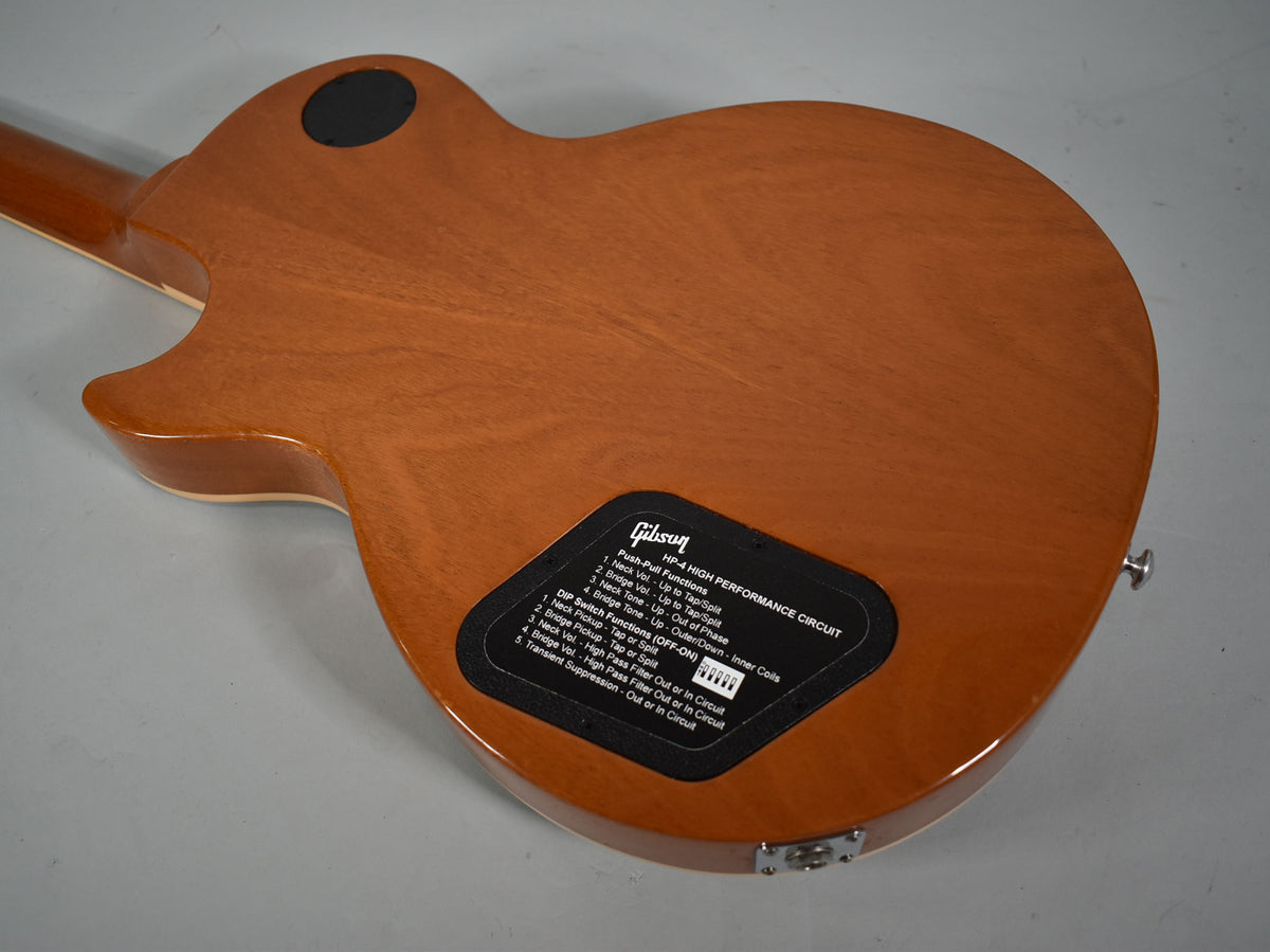 The back of the guitar shows a glossy, light brown finish with a black control cavity cover detailing the HP-4 High Performance Circuit.
