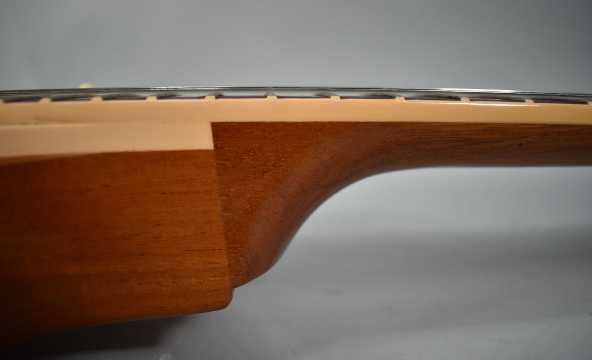 Side view of the guitar's neck heel, showing the natural wood grain and the cream binding along the fretboard edge.