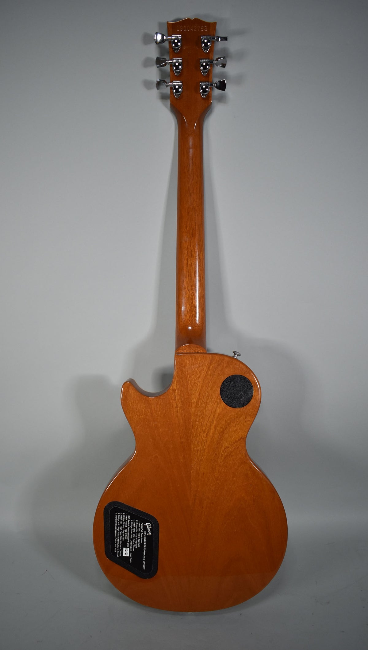 The guitar's back, neck, and headstock are visible, all in a glossy natural wood finish with chrome tuners.