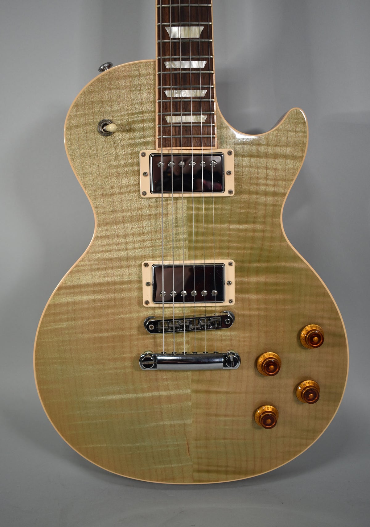Full front view of a seafoam green Les Paul with a flamed maple top, cream pickup rings, and amber speed knobs.