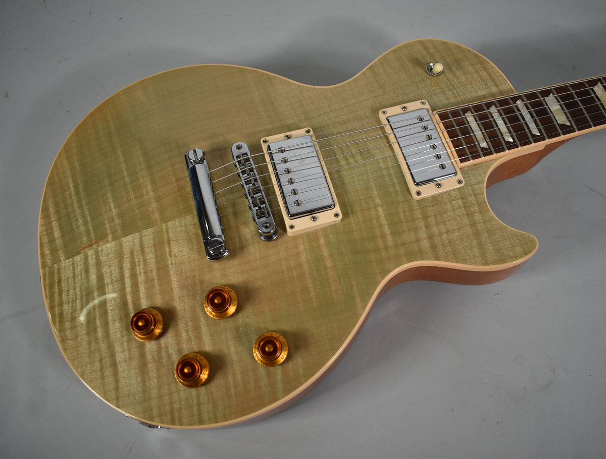 Overhead view of a seafoam green Les Paul with a flamed maple top, cream pickup rings, chrome hardware, and amber top hat knobs.