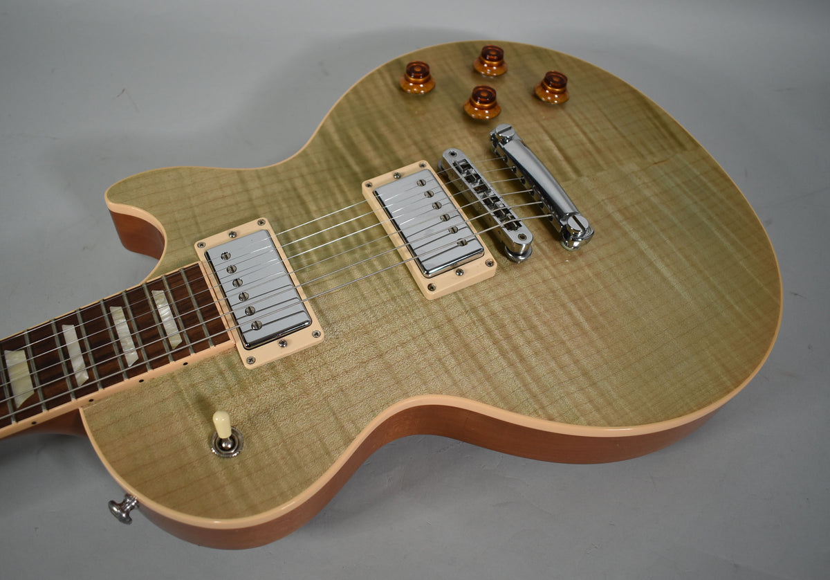 Close-up of a seafoam green flamed maple top electric guitar, showing the body, pickups, bridge, controls, and part of the fretboard.
