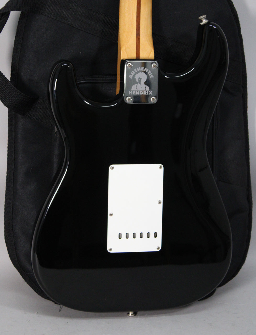 The guitar's glossy black back is shown, with a white tremolo cover and a four-bolt neck plate featuring a Hendrix silhouette.