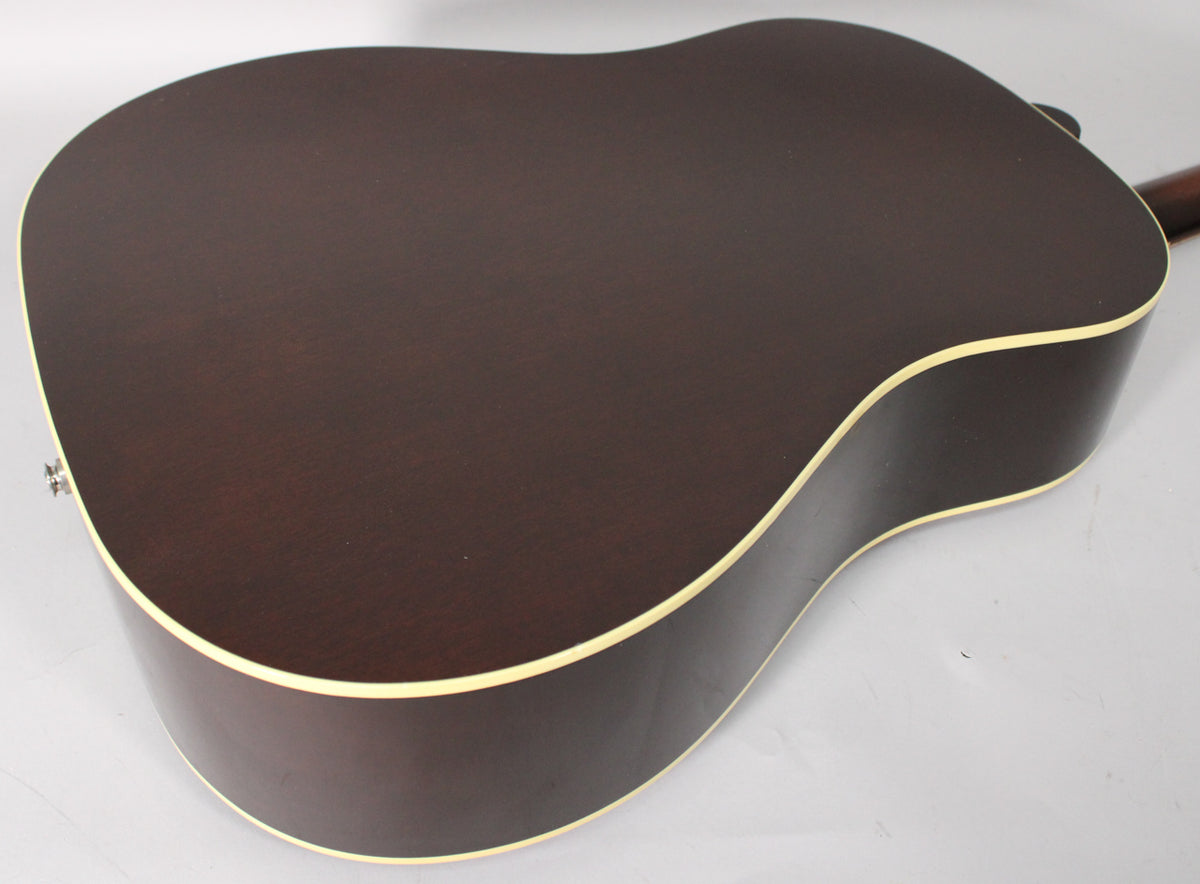 The back of a dark brown acoustic guitar, showing the lower bout and waist, with cream binding and a strap button.