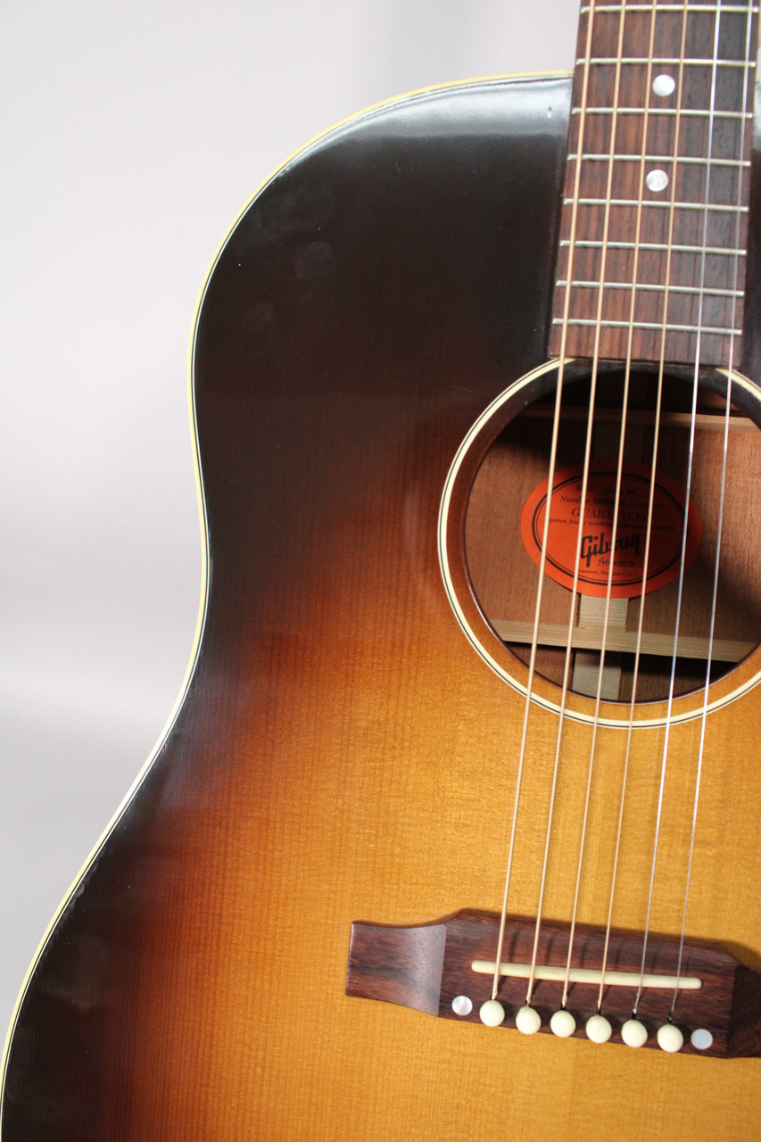 Close-up of the guitar's upper body, showing the sunburst finish, soundhole, fretboard, and bridge with white pins.
