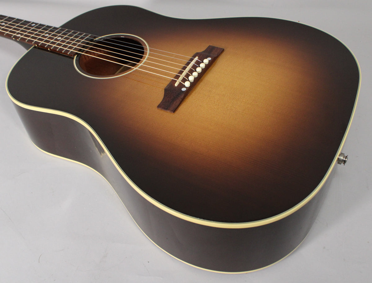 The acoustic guitar's sunburst body is angled, showing the soundhole, bridge with white pins, and a strap button on the lower bout.