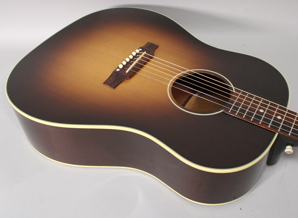 The acoustic guitar's sunburst body, with a dark brown back and sides, is angled to show the light-colored binding and soundhole.
