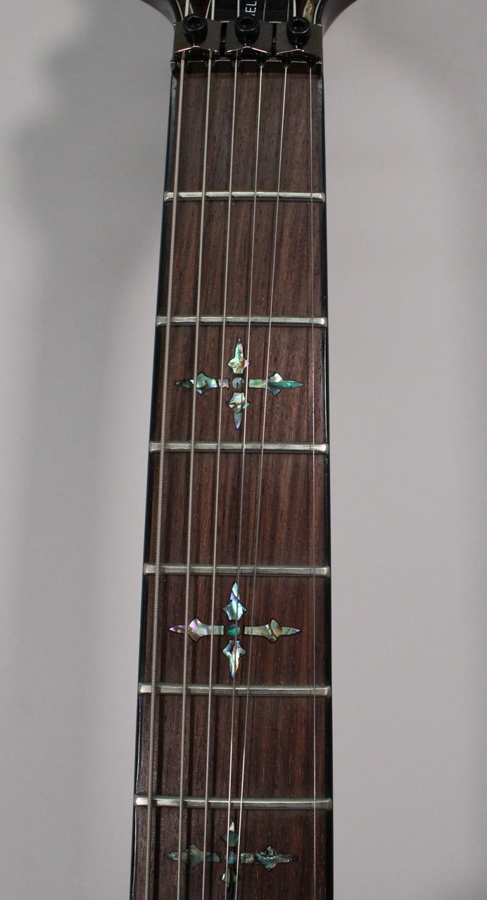 Close-up of the dark rosewood fretboard with abalone cross inlays and a black locking nut at the top.