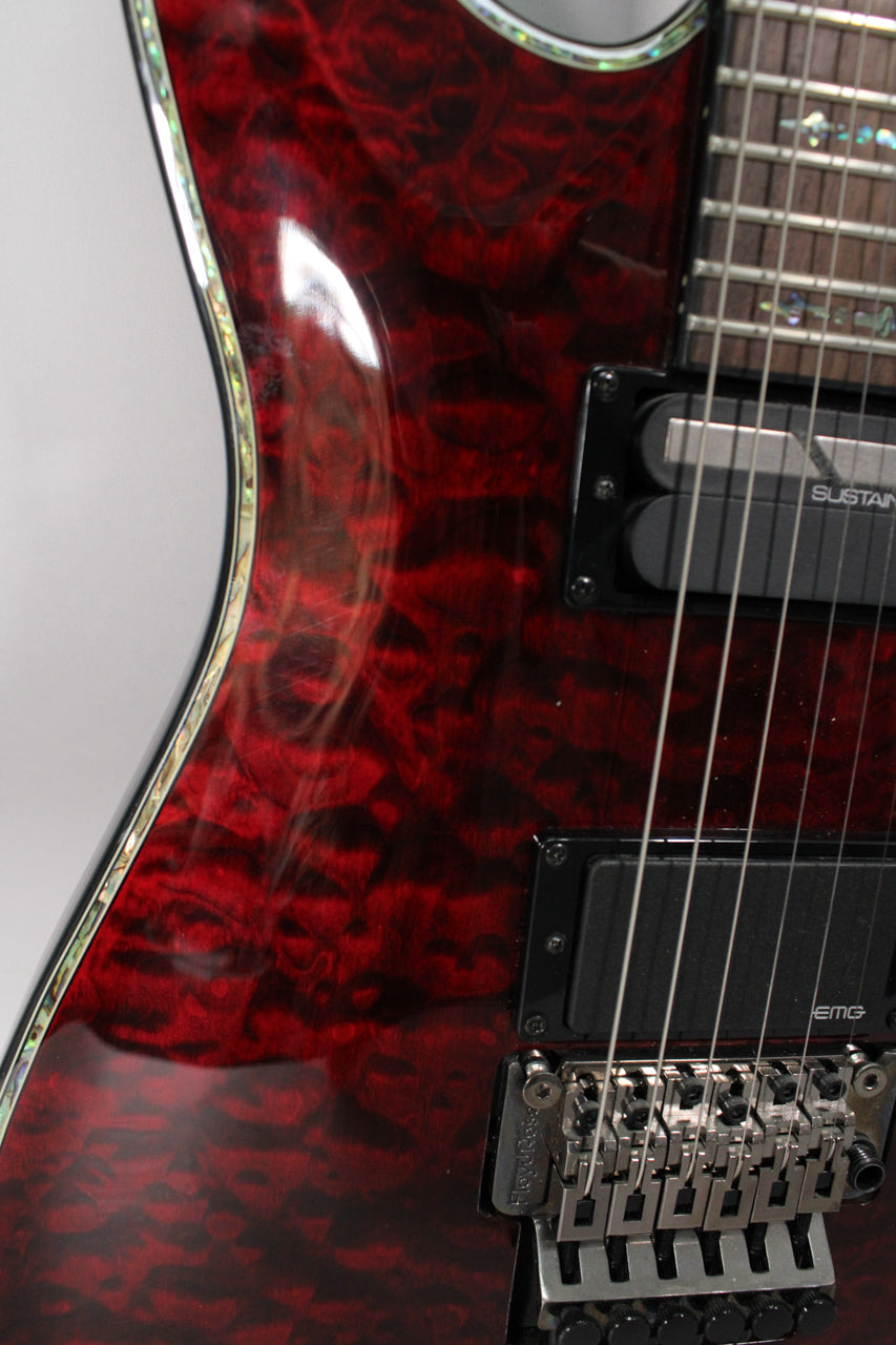 Close-up of the guitar's upper body, showing the glossy black cherry finish with dark figuring, abalone binding, and black hardware.