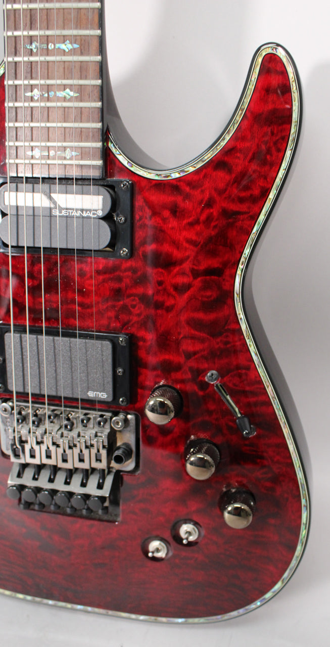 Close-up of a dark cherry burst electric guitar with a flamed maple top, abalone binding, two humbuckers, and a Floyd Rose bridge.