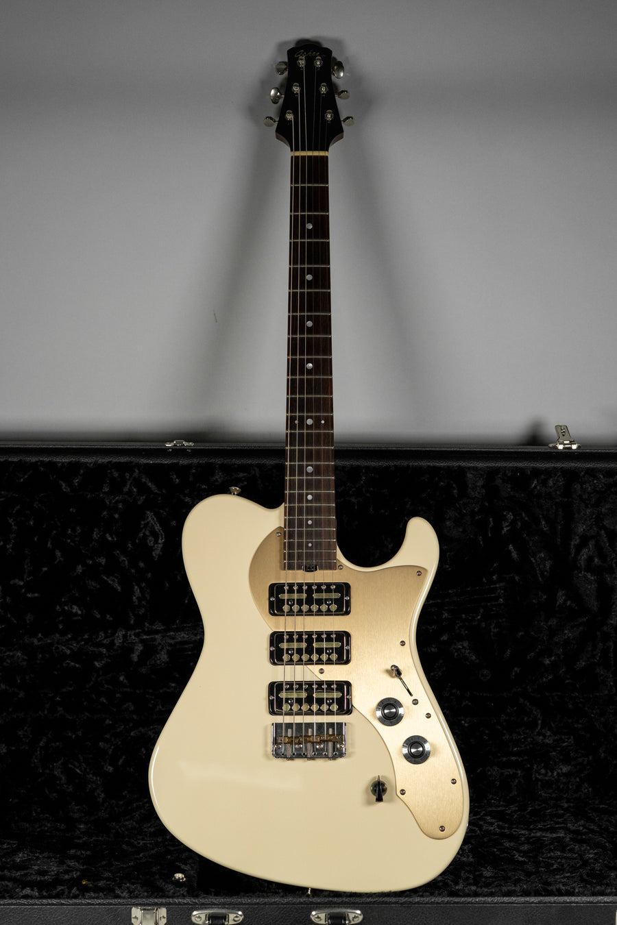 Full-length view of an antique white electric guitar with a gold pickguard, three black pickups, and two chrome control knobs.