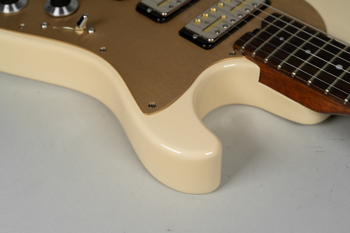 Close-up of the guitar's lower bout in antique white, showing the gold pickguard, two gold foil pickups, and the neck joint.