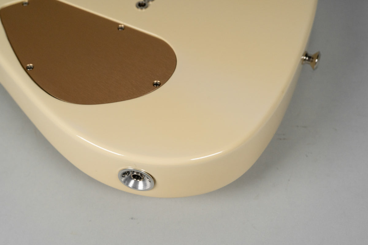 The lower bout of the antique white guitar body, showing the output jack, strap button, and a copper control cavity cover.