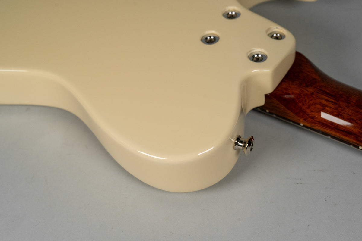 The guitar's antique white body, with a glossy finish, shows a chrome output jack and four chrome neck bolts on the back.