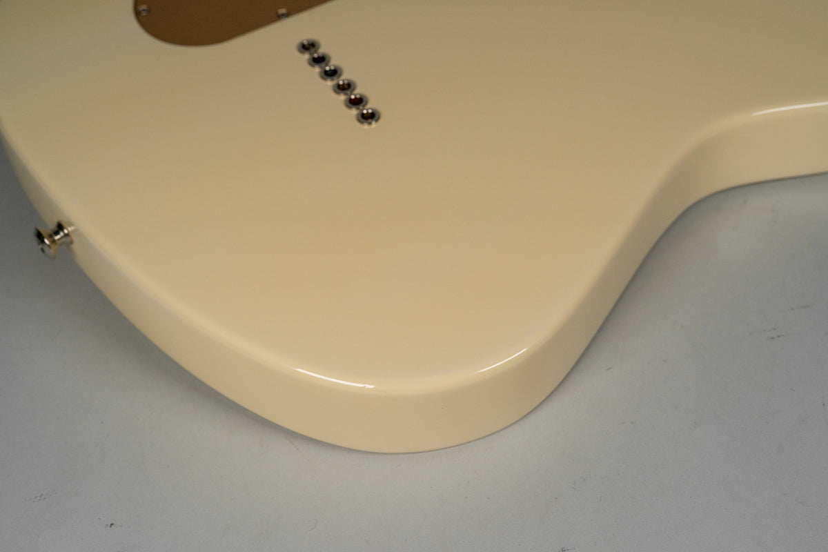 The back of an antique white guitar body, showing six string ferrules and a strap button, with a glossy finish.