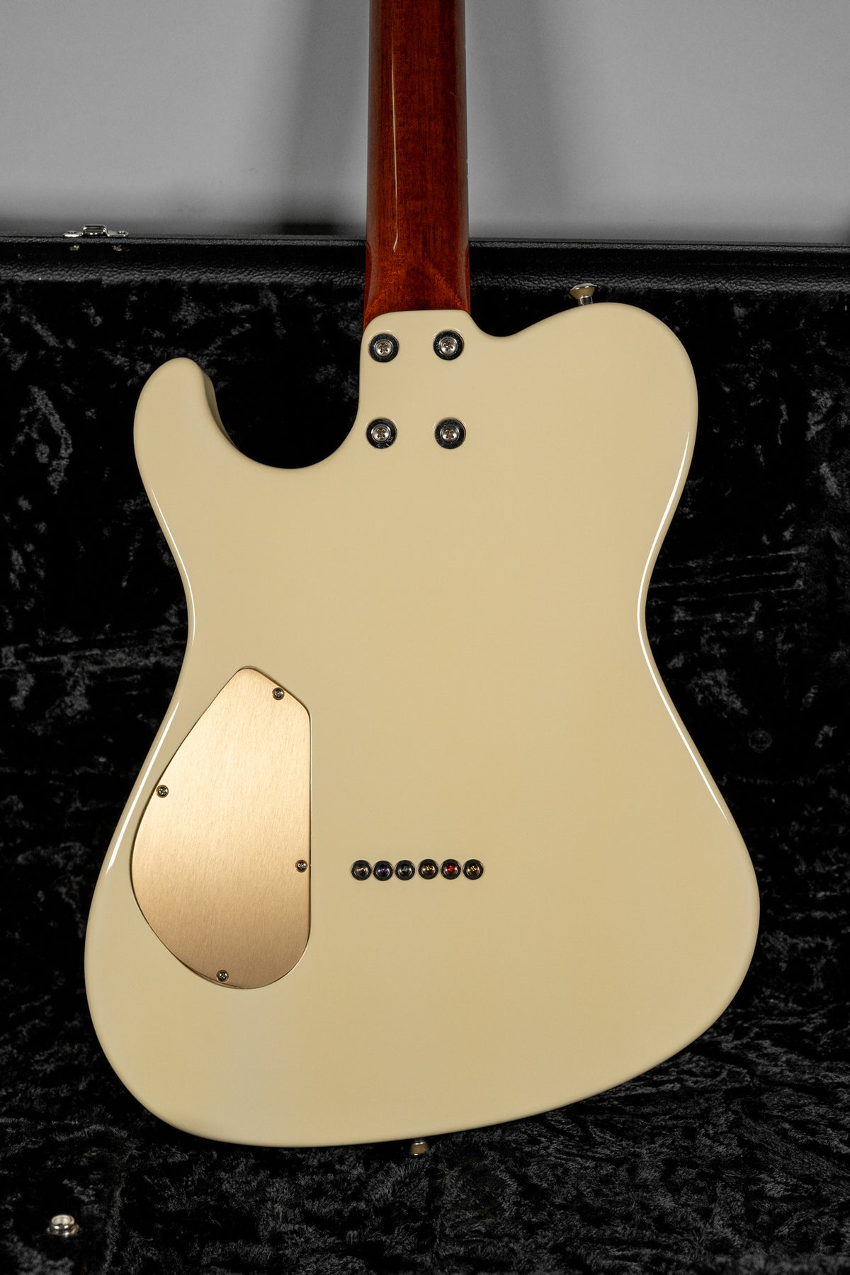The back of an antique white guitar with a dark wood neck, a brushed gold control plate, and six string-through ferrules.