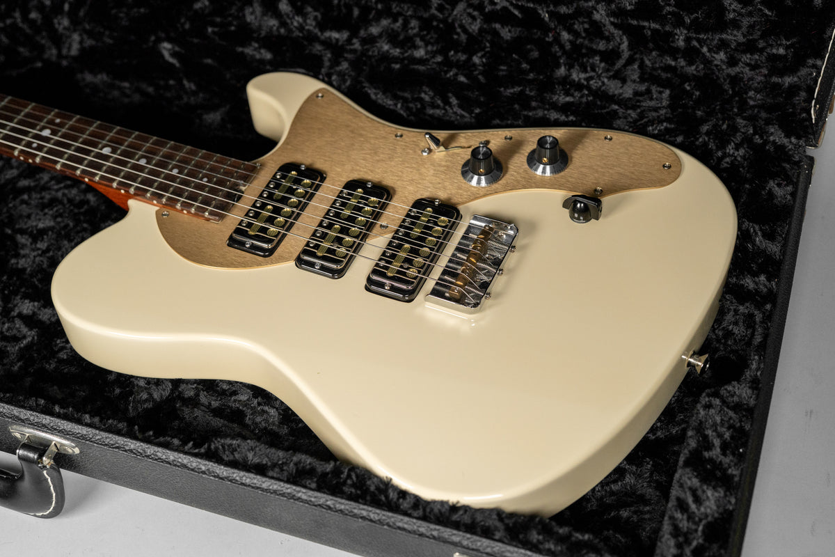 The antique white electric guitar, with a light wood pickguard and three black Lollar Gold Foil pickups, rests in a black velvet case.