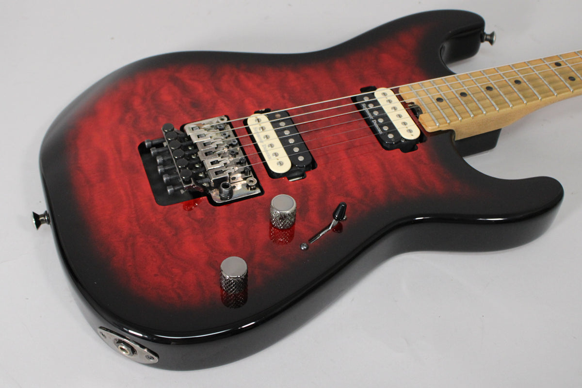 The guitar's translucent red burst finish with black edges is visible from the upper body, showing a Floyd Rose tremolo and two cream humbuckers.