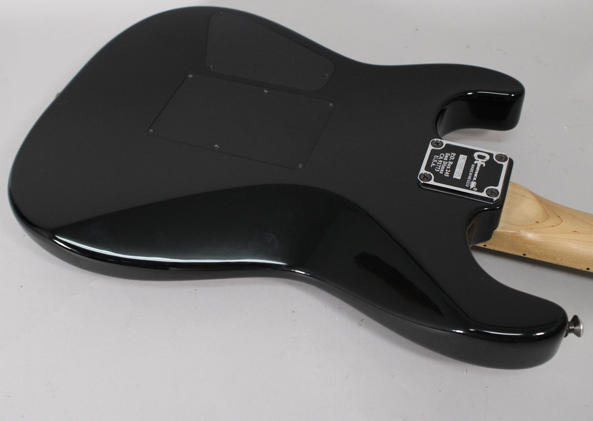 The guitar's glossy black back is angled, revealing two control cavity covers, a neck plate, and a light wood neck.