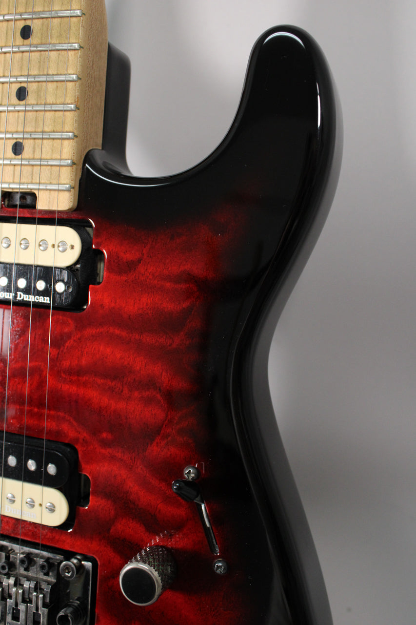 Close-up of the guitar body's upper bout, showing the transparent red burst finish, two cream humbuckers, and a single black control knob.