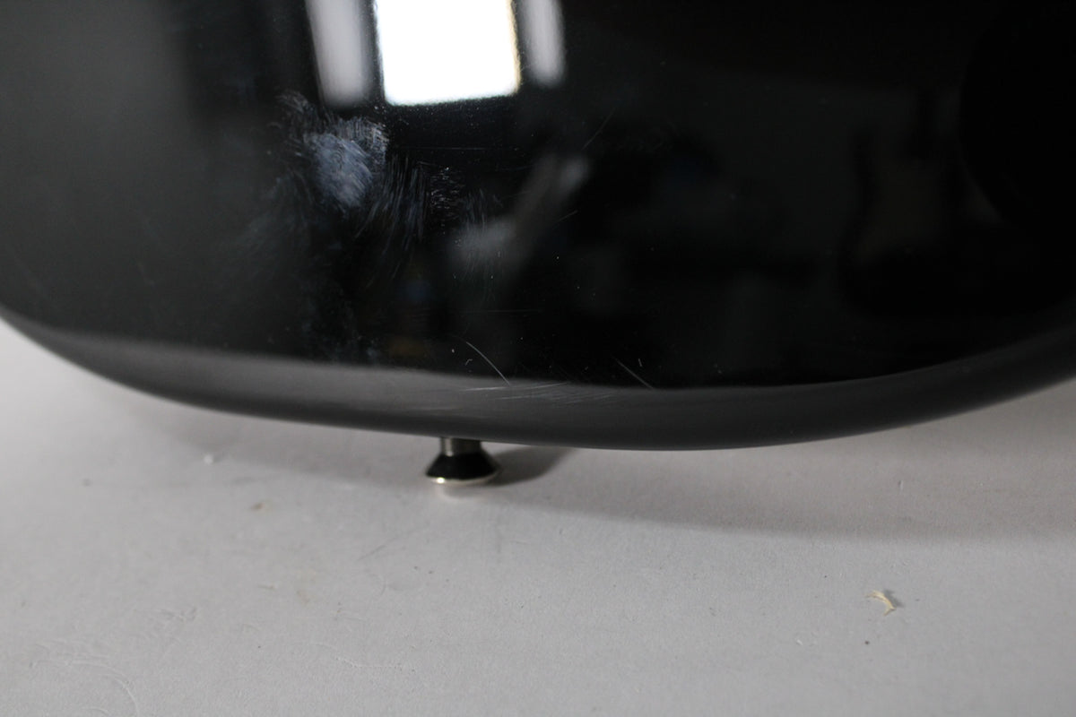A close-up of the guitar's lower body, showing light scratches and swirl marks on the glossy black finish, with a strap button visible.