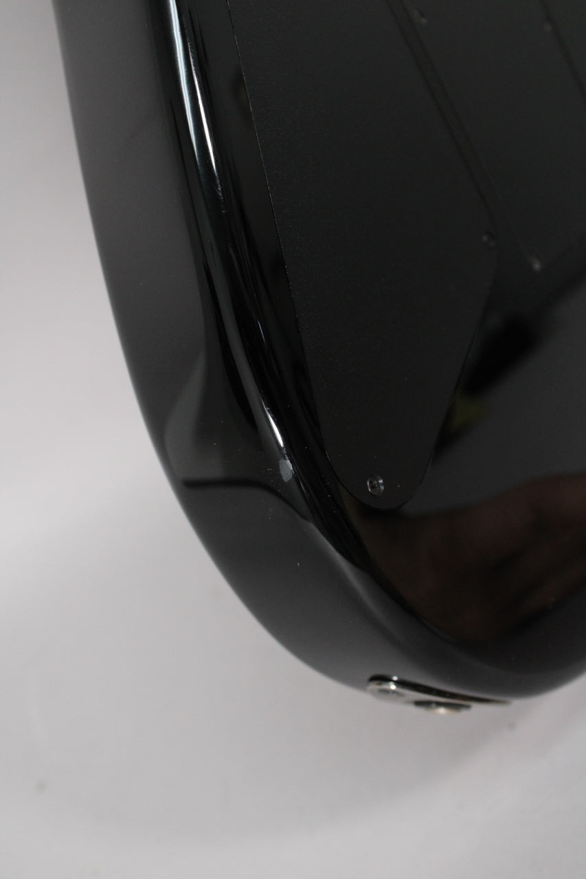 Close-up of the guitar's lower bout, showing a small ding on the glossy black finish and the output jack.