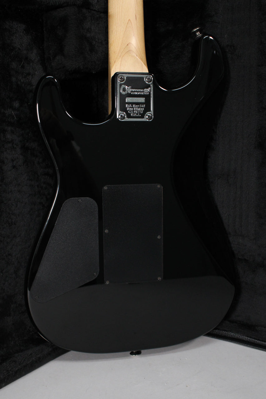 The guitar's glossy black back, with a natural wood neck and chrome neck plate, shows two black control cavity covers.