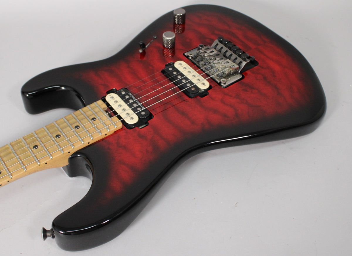 The guitar's red burst body with black edges is angled from the lower left, revealing a maple fretboard and two cream-colored humbuckers.