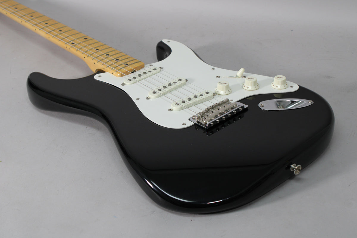 Black Stratocaster body with a white pickguard, three single-coil pickups, chrome tremolo bridge, and cream control knobs.