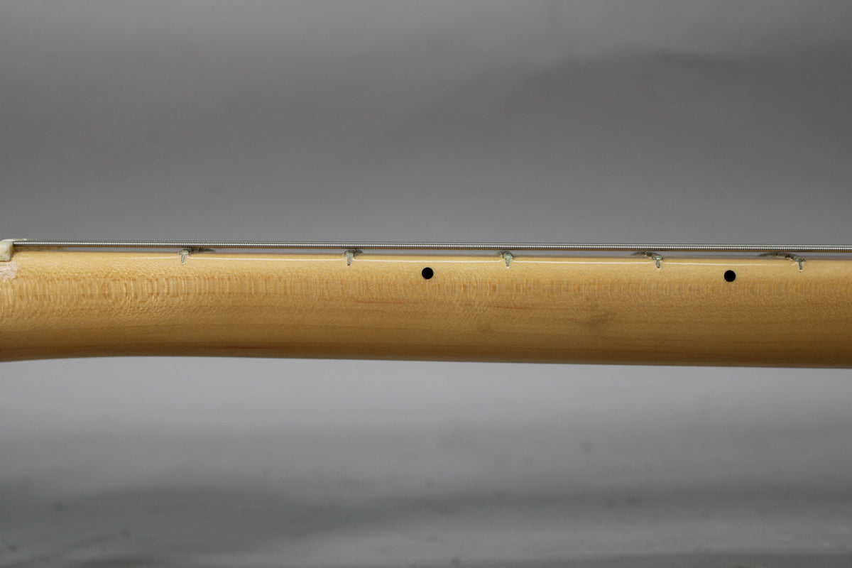 Close-up of the light wood guitar neck with strings, frets, and two black dot inlays.