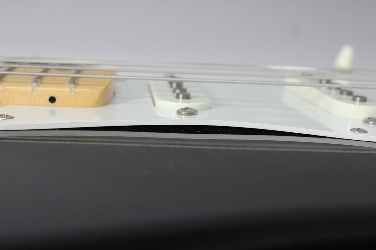Close-up of the black guitar body and white pickguard, showing a slight gap between them near the middle pickup.