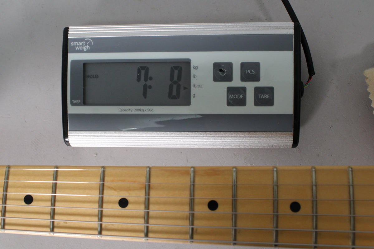 A digital scale displays "7.8" above a maple fretboard with black dot inlays and light fret wear.