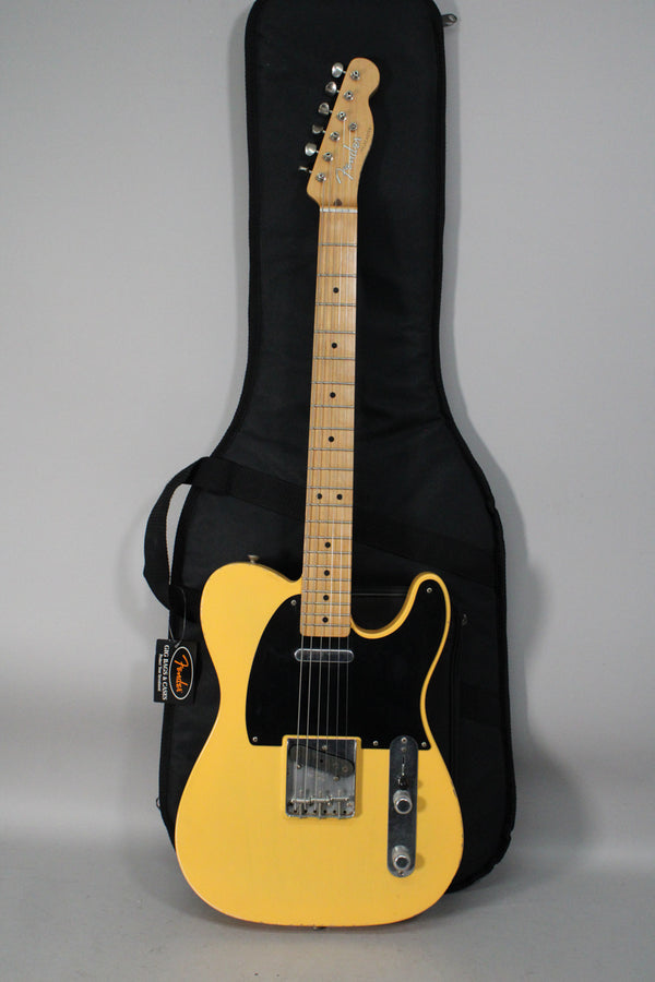 Full-length view of a butterscotch blonde Telecaster with a black pickguard, maple neck, and visible wear on the body and control plate.