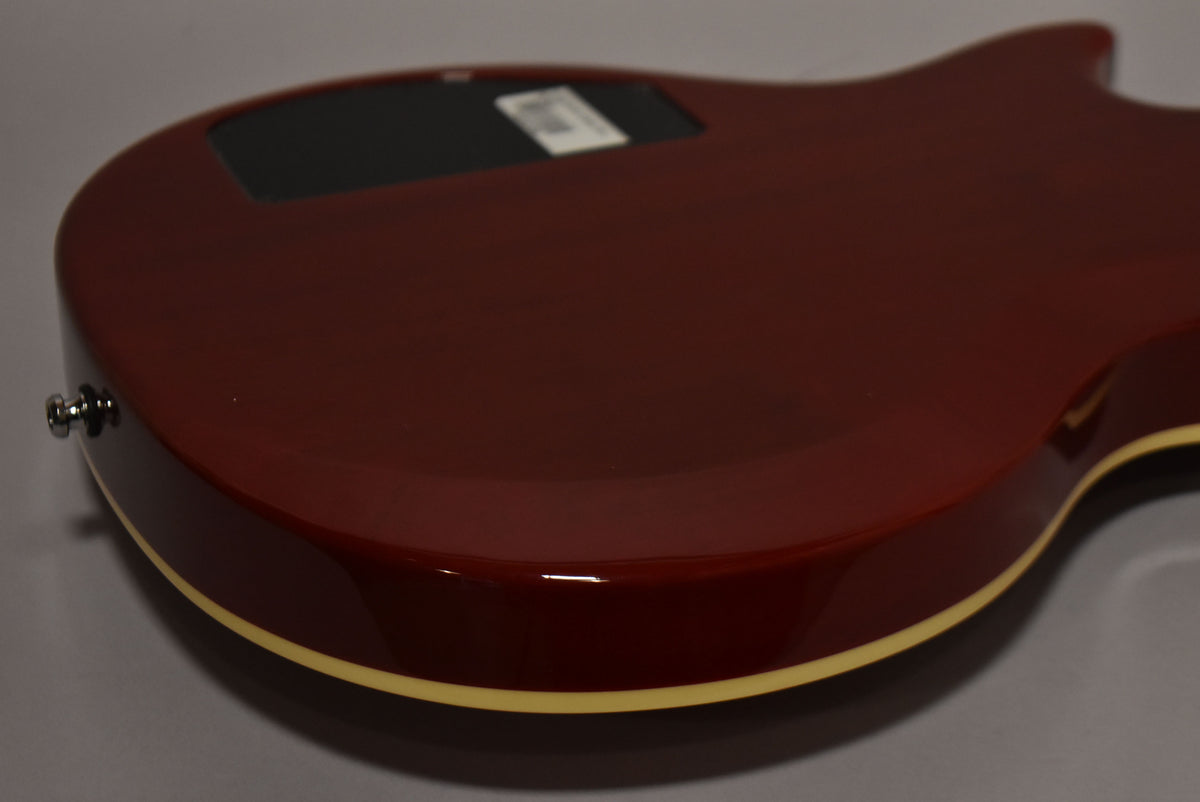 The guitar's cherry burst back, with cream binding and a black control cavity cover, is shown from a low angle.