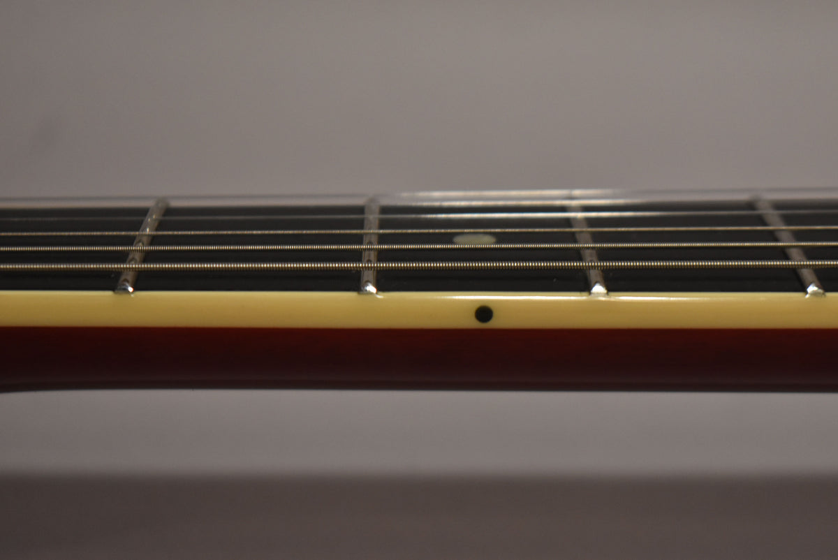 Close-up of the guitar's neck from the side, showing the dark fretboard, cream binding, and a black dot side marker.