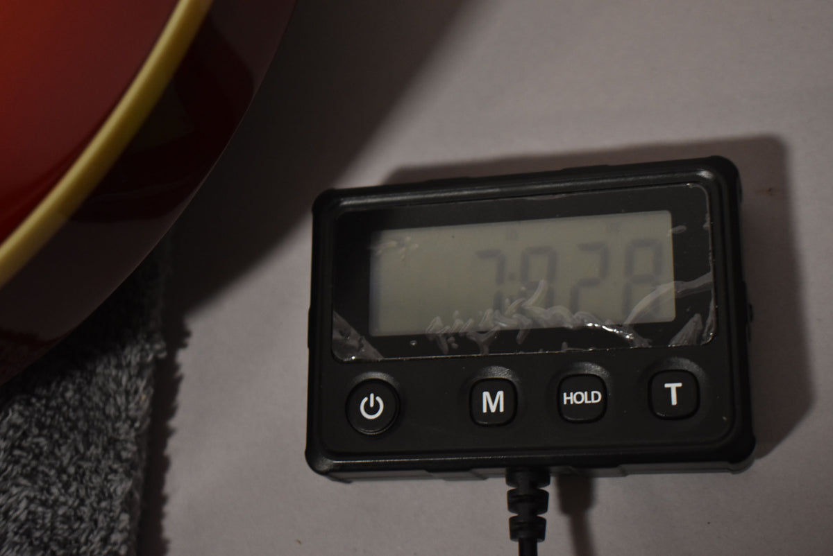 A digital scale displays "7.928" next to the guitar's cherry burst body with cream binding, resting on a gray cloth.