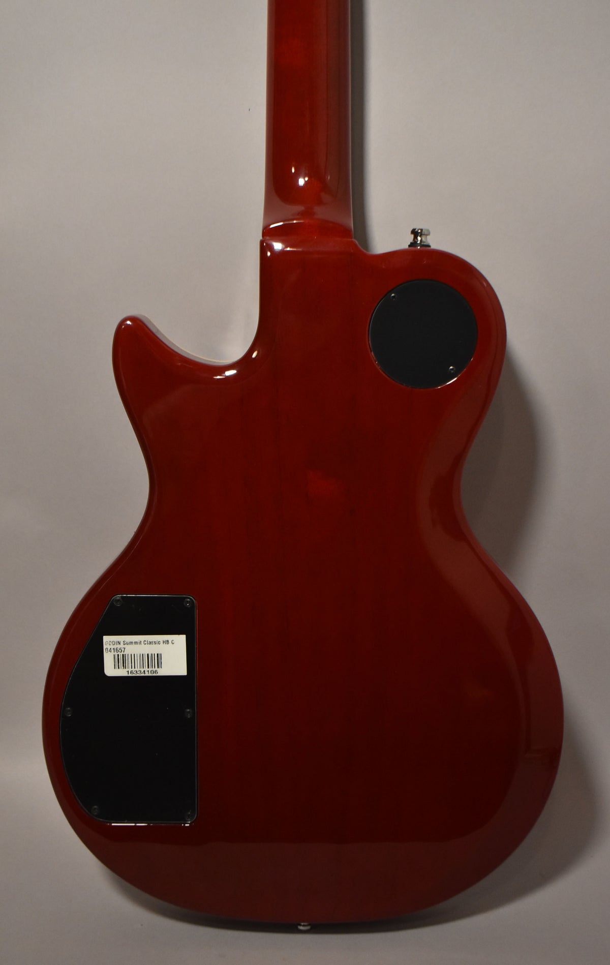 Full back view of a cherry burst electric guitar with a glossy finish, showing two black control cavity covers.