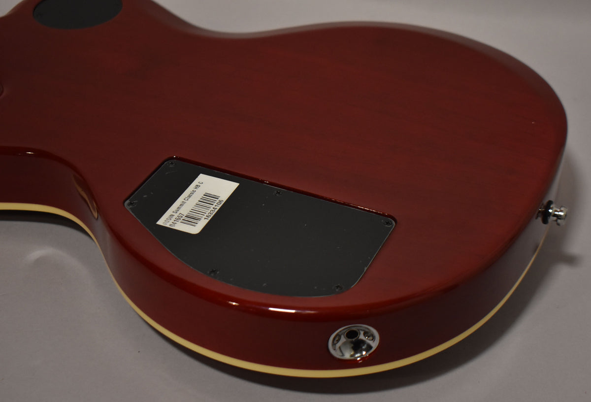 The back of a cherry burst guitar with cream binding, showing the control cavity cover and output jack.