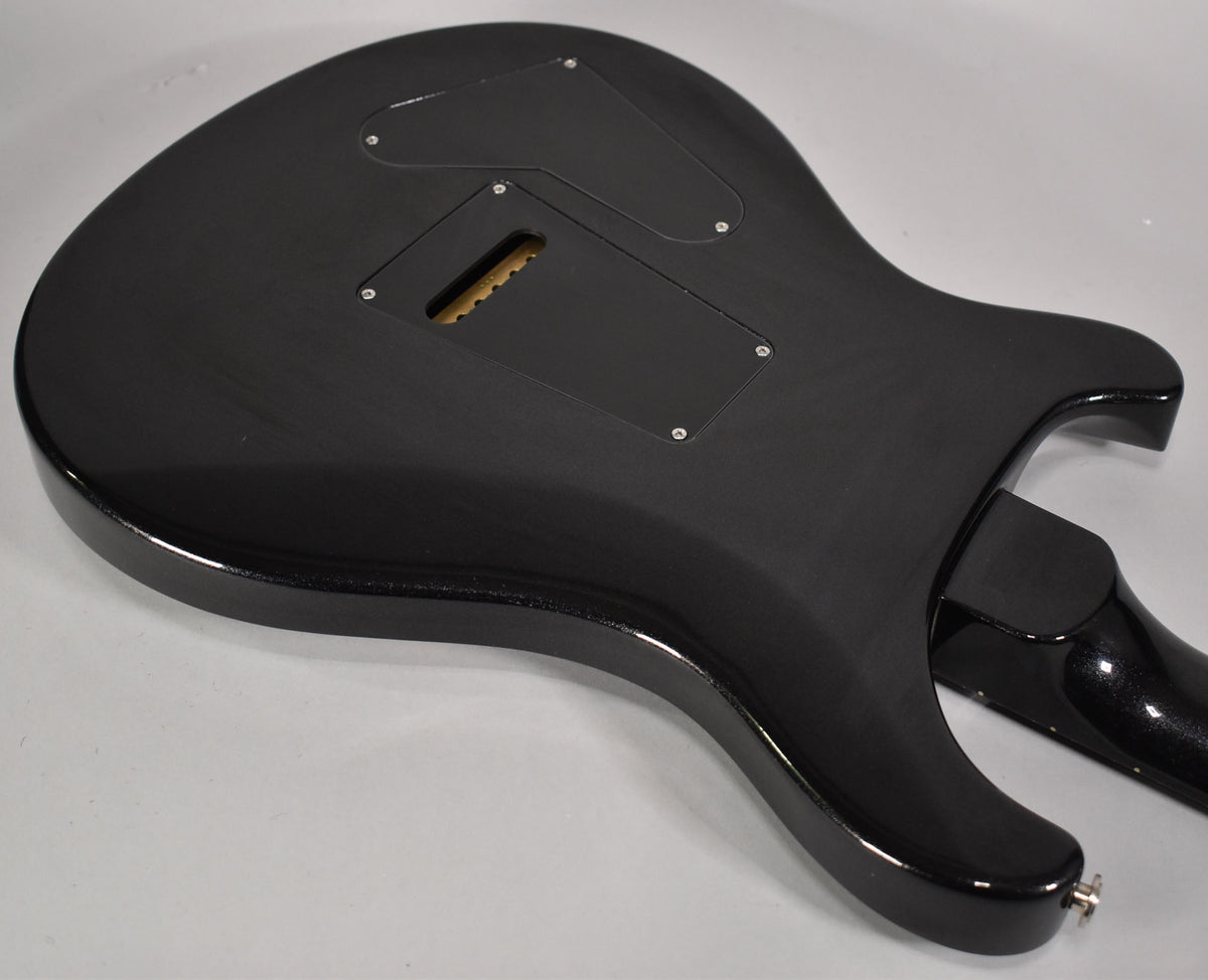 The guitar's glossy black back, with two control cavity covers and a tremolo spring cavity, shows light surface scratches.